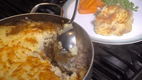 Hot cottage pie / shepherd’s pie being served onto plate with carrots and peas. Stock-Footage 104124420