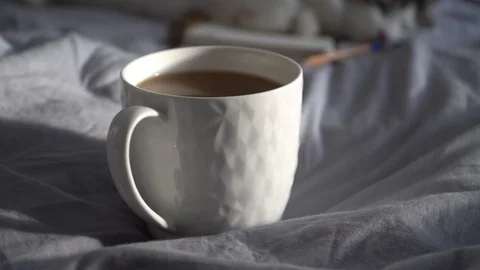 Hot cup of coffee with notebook and pencil on a bed. 動画素材 112509321
