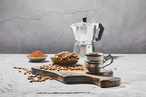 Hot cup of espresso with coffee beans scattered on wooden board and a pot und Stock-Fotos