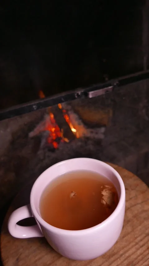 A hot cup of ginger tea with honey on a table. A hot tea by the fireplace Stock Footage 339042291
