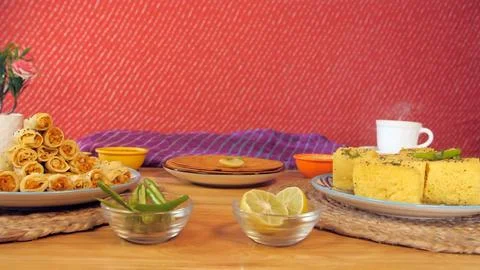 A hot cup of tea placed with Gujarati snacks Khaman Dhokla, Khandvi, and Khakra Stock Photos