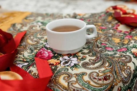 A hot cup of tea is on a table, the entourage of a Russian village, a scarf with Stock Photos