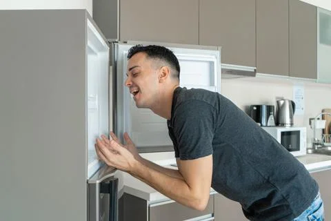 On a hot day, the guy cools with his head in the refrigerator. Broken air con Foto stock