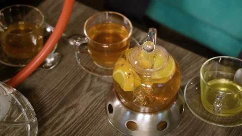 Hot delicious fruit tea in a teapot and cups on a wooden table. Stock Footage 106583201