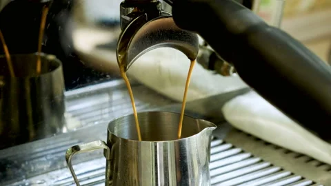 Hot drink. Close-up shot of coffee machine pouring espresso in a metal jug. 4K Video stock 87805917