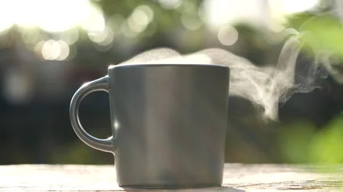 Hot drink coffee cup. A steaming cup of coffee on wood table in the morning sun Stock Footage 241929609