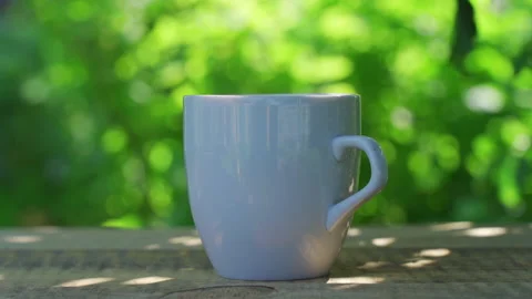 Hot drink in a cup against the background of a summer garden in the morning Stock Footage 223692987