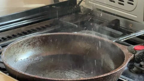 Hot empty frying pan with steam rising on gas stove. Cooking surface after Video stock 336978453