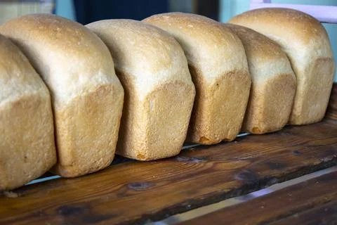 Hot freshly cooked bread is placed in trays in the bakery. Stock Photos