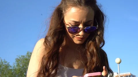 Hot girl uses her smartphone in the park Stock Footage