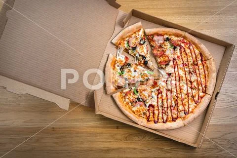 Hot italian pizza in the cardboard box on the wooden table in restaurant. Top Stock Photos