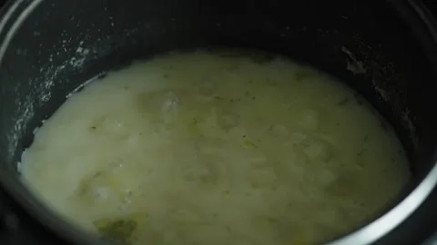 Hot liquid mixture with potatoes bubbles gently inside a pot. Stock Footage 339210106