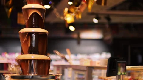 Hot melted chocolate flows down a chocolate fountain.  Stock Footage 322546717