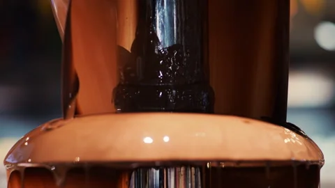 Hot melted chocolate flows down a chocolate fountain.  Stock Footage 322549692