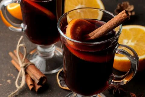 Hot mulled wine with cinnamon and orange in glass cups close-up on a dark bac Stock Photos
