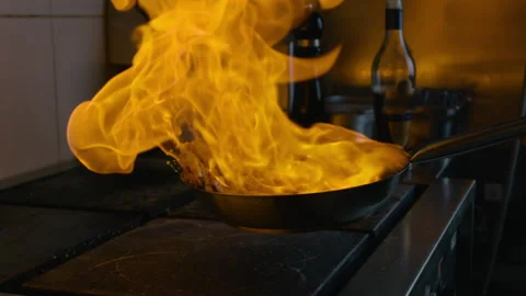 On a hot pan cooked shrimp. Set fire to. Slow Motion. Dark kitchen. Stock Footage 131323426