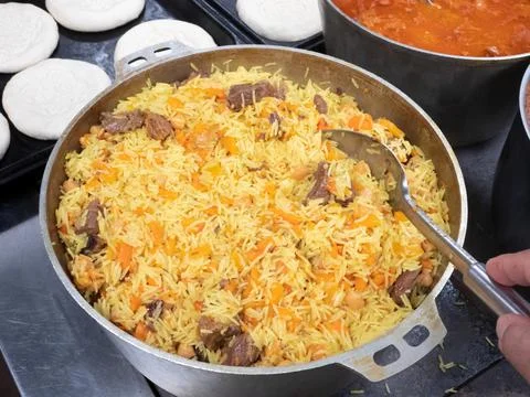 Hot pilaf in a large pan. Eastern cuisine Stock Photos