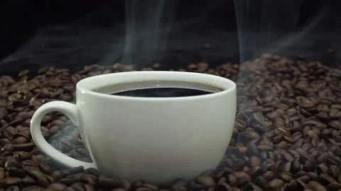 Hot roasted coffee beans with soft smoke drifing behind a coffee mug Stock Footage 182471923