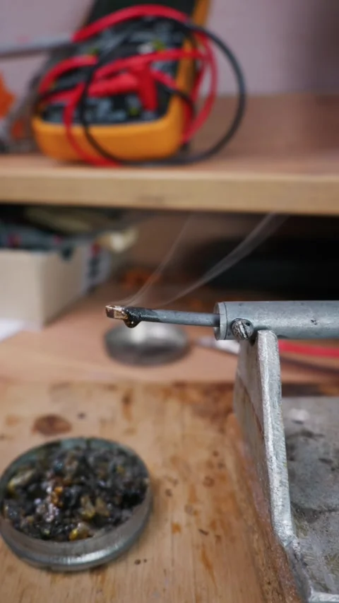 Hot Soldering Iron Tip Emitting Smoke Above Rosin Tin in Workshop Stock Footage 338331469