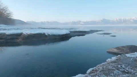 Hot spring steam drifting over frozen lake shore Stock Footage 245041547