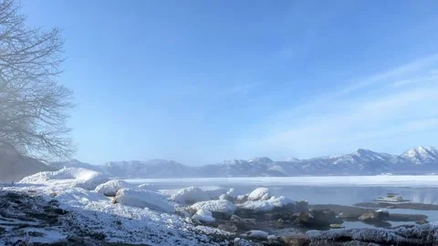 Hot spring steam drifting over lake shore in winter Stock Footage 245794056