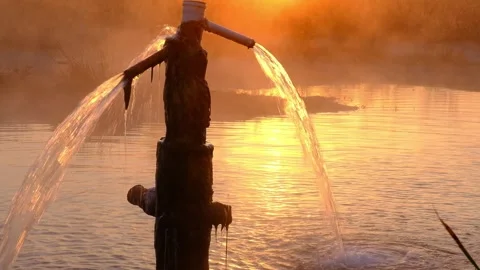 Hot spring water pouring from a pipe into a natural pool at sunrise Stock Footage 345155099