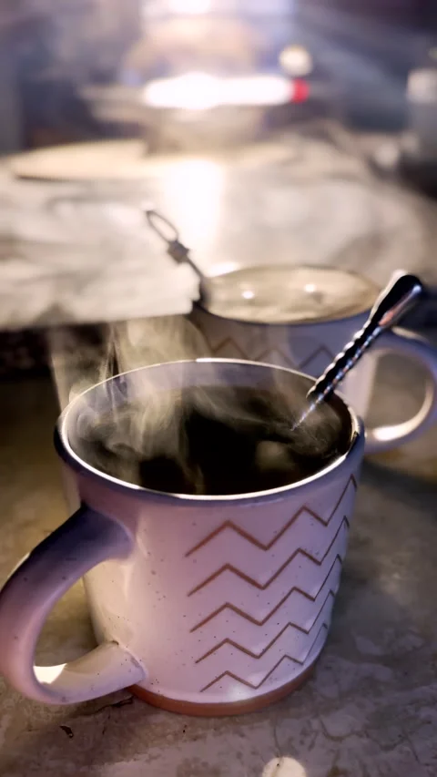 Hot steam rises from coffee mugs backlit by golden hour sunlight Stock Footage 344010468
