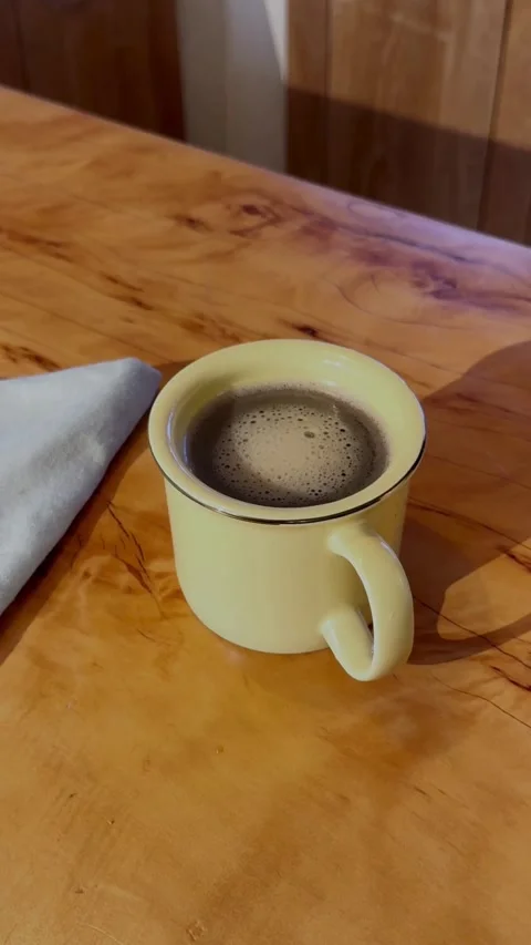 Hot steaming coffee in yellow mug on wooden table Stock Footage 331773386