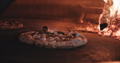 Hot steaming pizza being cooked in a brick oven wood fired Stock Footage 105310088