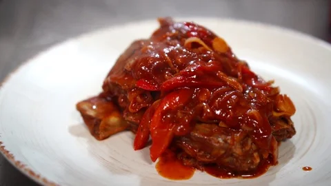 Hot steaming pork meat ragout under tomato sauce on white plate restaurant meal Stock Footage 106979679