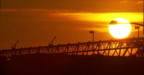 Hot sun creating fiery red sky sets behind construction materials Stock Footage 67275097
