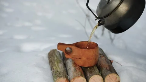 Hot tea from a camping kettle is poured into a kuksa. Видео 304167080