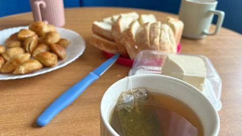 Hot tea in ceramic mug with tea bag close-up on blurred food dining table Stock Photos