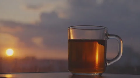 Hot tea with chamomile flower on windowsill at evening sun Stock Footage 246329177