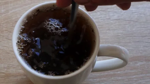 Hot tea in a cup is stirred with a spoon. Medium shot. Vidéo 320563163