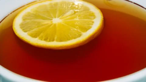 Hot tea with floating lemon slice in white cup close-up 写真素材