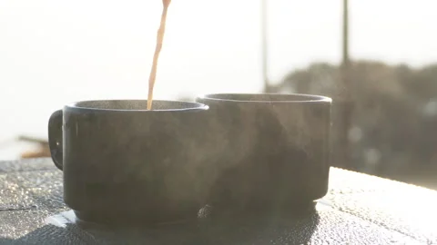 Hot Tea or Coffee Being Poured Into Cup With Rising Steam in Morning Light Stock Footage 326047646