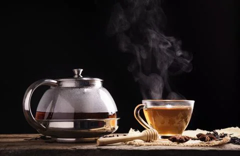 Hot tea placed on a table with a pitcher on a black background Stock Photos