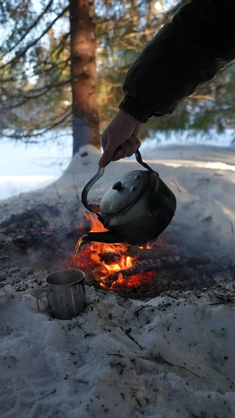 Hot tea is poured from a camp kettle into a metal mug 스톡 동영상 329969072