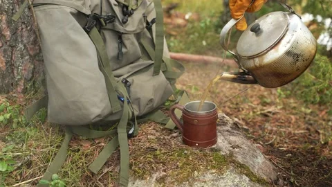 Hot tea is poured from the camping kettle into a cup. Travel and camping concept 動画素材 237709130
