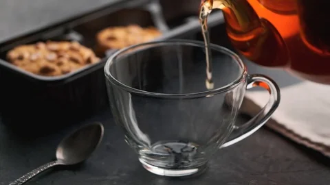 Hot tea is poured into a transparent cup and slowly emits steam Stock Footage 128579653