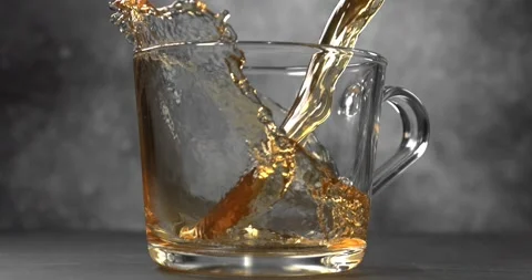 Hot tea pouring into glass cup slow motion Stock Footage 345977005