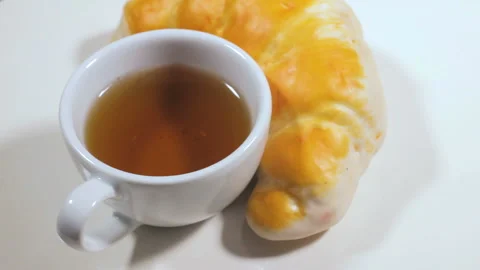 Hot tea with tasty roll, white background Stockbeeldmateriaal 87923458