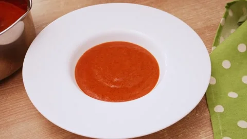 Hot tomato and red pepper soup being poured from ladle into white ceramic Stock Footage 344886189