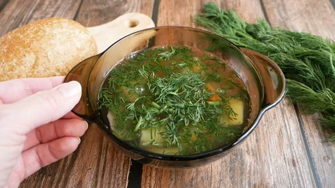 Hot vegetables soup in plate with green onion and bread on wooden table Stock Footage 124751237