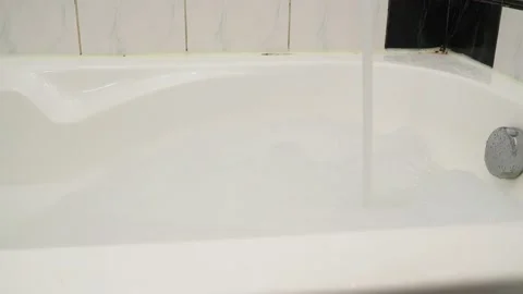 Hot water for bathing, fluffy white foam is drawn from the tap into the bath 库存影片 150517963