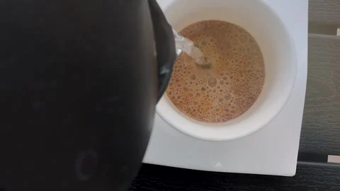 Hot water being poured from a kettle into a white cup Видео 333763786