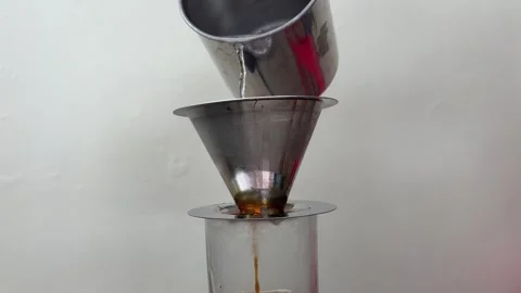Hot water is poured into a drip coffee filter set on a glass Stock Footage 312587730