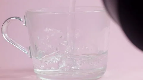 Hot water is poured into a transparent cup on a pink background, Stock Footage 172405341