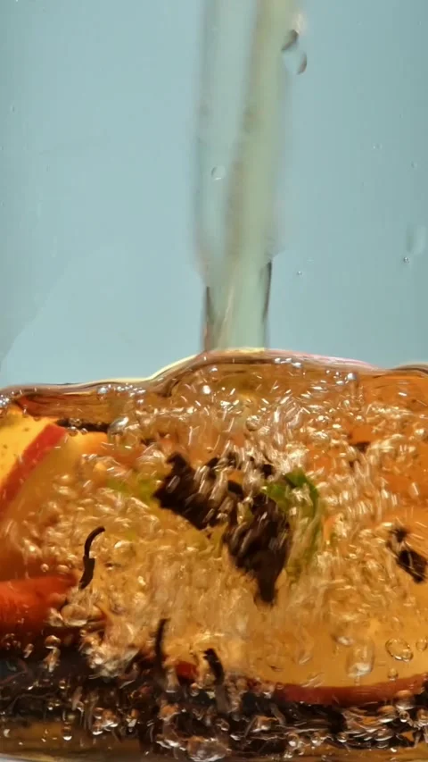 Hot water pours over apple, lemon, mint and cinnamon with black tea leaves; cozy Stock Footage 314706617